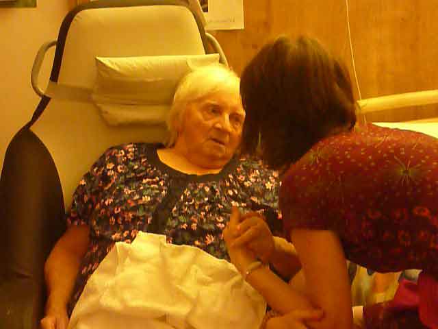 Une femme écoutant attentivement une dame âgée, un échange intime dans une chambre d'hôpital.