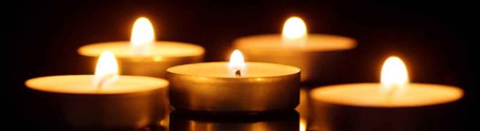 Un ensemble de bougies allumées dans une atmosphère sombre, créant une ambiance chaleureuse et méditative.